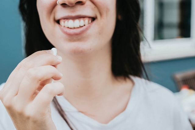 Woman smiling holding a probiotic pill in her hand